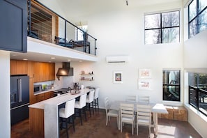Una cocina moderna con una isla central, asientos en la parte superior y ventanas amplias.