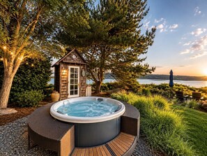 A hot tub surrounded by a wooden deck, a small wooden structure, and a view of a lake. - Langley Waterfront Oasis with Hot Tub (Langley)