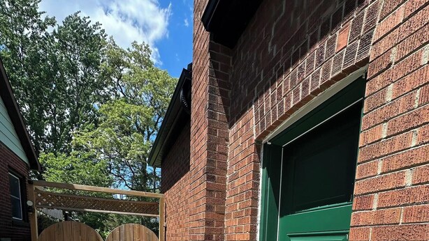 A brick building with a green garage door, a wooden gate, and a portable air conditioning unit. - Bluffs suite retreat - beautiful cliffcrest leafy suburb moments from the beach! (Toronto)
