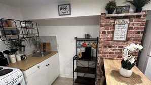 A kitchen with a brick accent wall, a wooden dining table, and a hanging plant. - Bluffs suite retreat - beautiful cliffcrest leafy suburb moments from the beach! (Toronto)