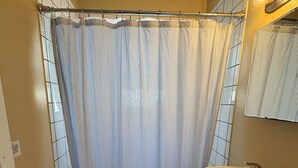 Ett badrum med toalett, handfat och duschdraperi.