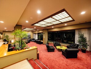 A hotel lobby with a reception desk, seating area, and large windows. - SANEIKAKU (Matsumoto)