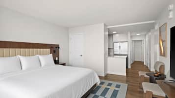 Habitación de hotel con una cama grande, un escritorio, una silla, una mesita, un televisor y una puerta que da a un baño.