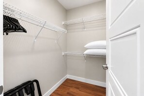 A walk-in closet with white shelving units, a radiator, and a wooden floor. - Large Corner 2 Bedroom/2 Bath Unit with Floor to Ceiling Lake Superior Views (Duluth)