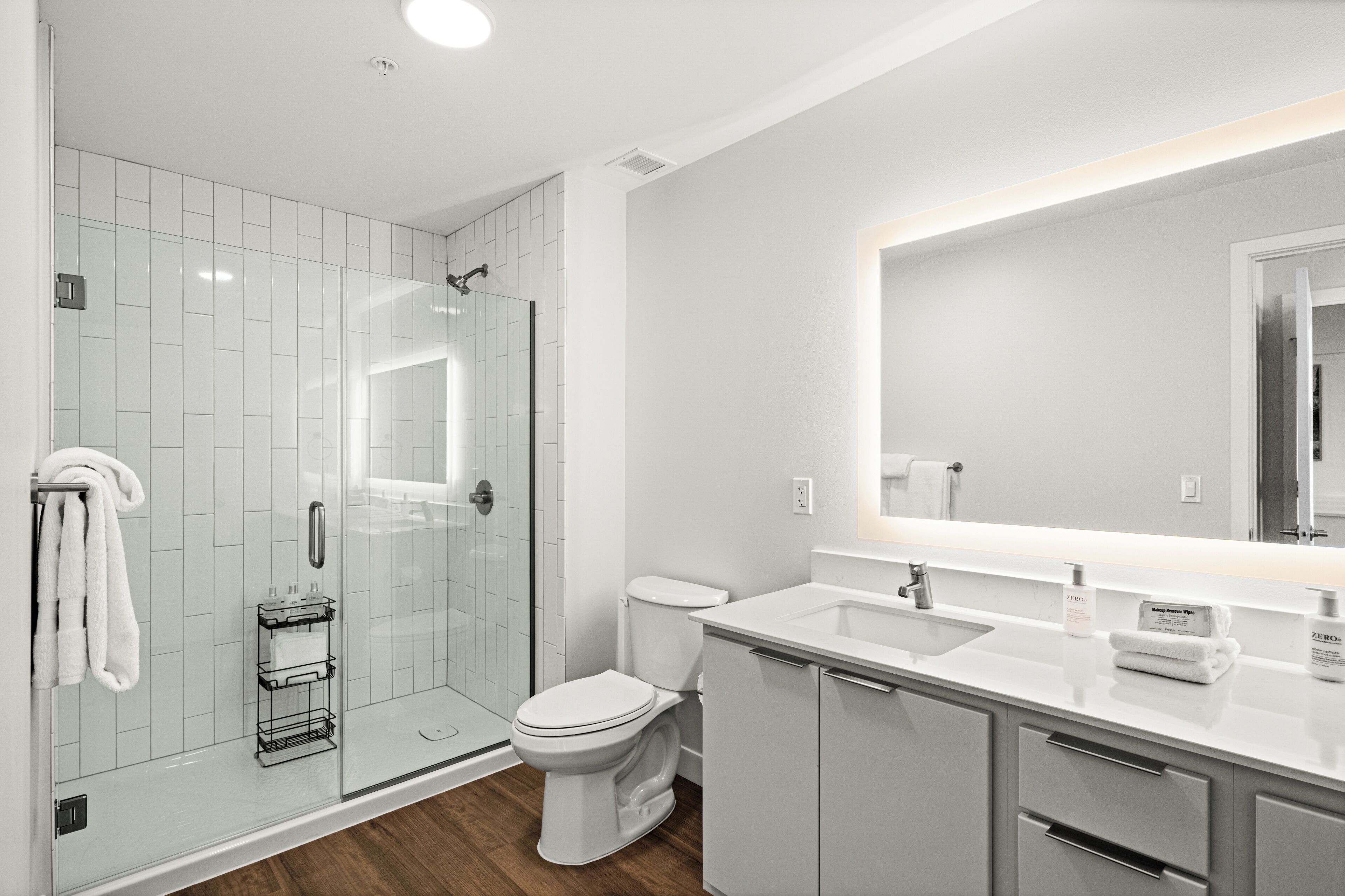 A modern bathroom with a glass-enclosed shower, a toilet, a sink, and a mirror.