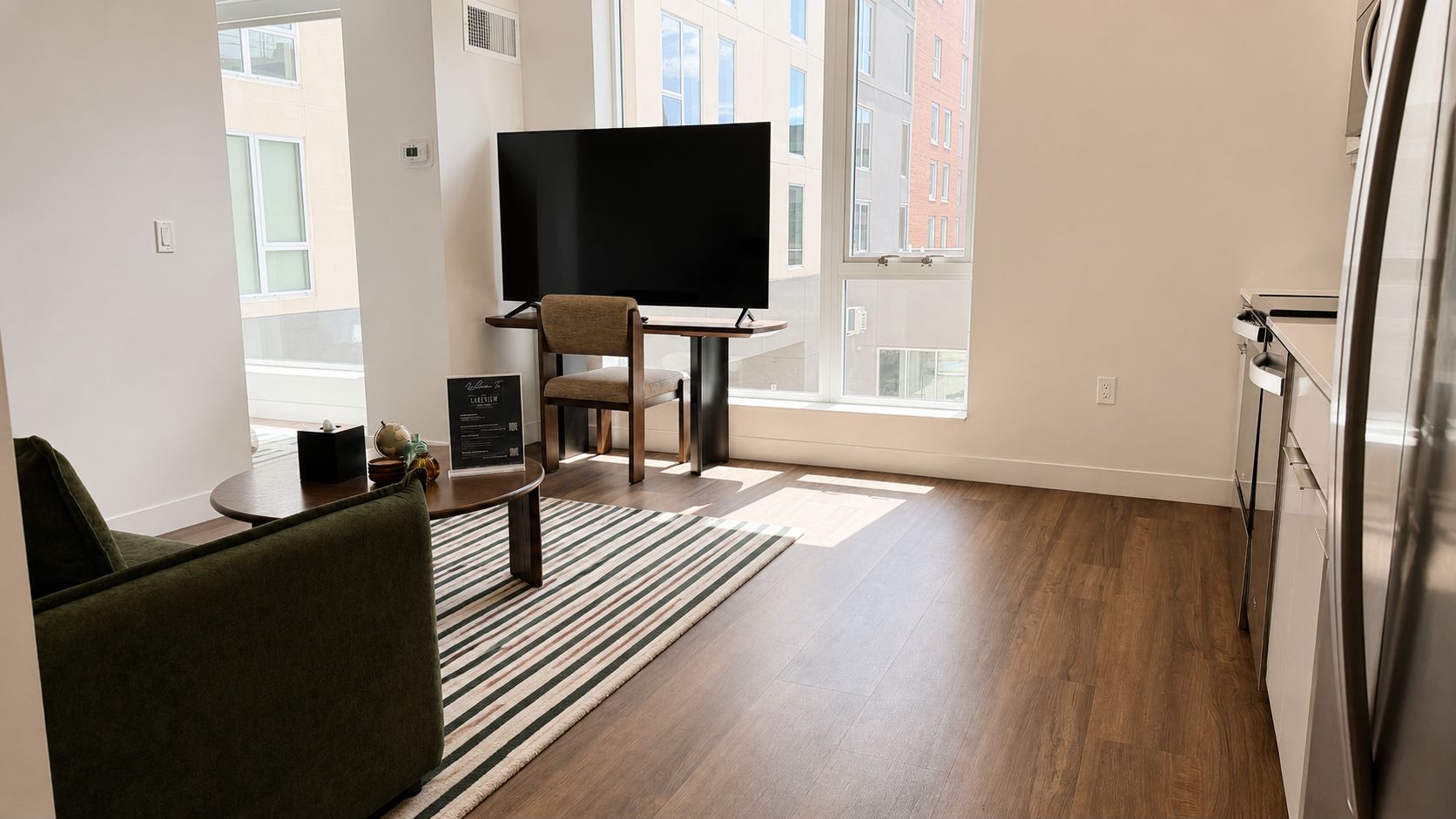 A modern living room with a flat-screen TV, a sofa, a coffee table, and a striped rug.