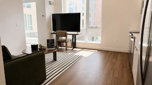 Un salon moderne avec un téléviseur à écran plat, un canapé, une table basse et un tapis à rayures.