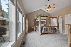 Ein Schlafzimmer mit einem Himmelbett, einem Deckenventilator und großen Fenstern.