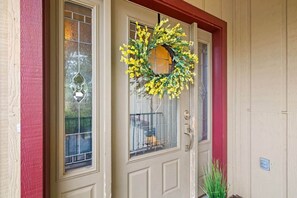 Una casa con puerta principal color beige, detalles en rojo y una corona en la puerta.