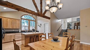 A spacious kitchen with wooden cabinets, a large island, and a dining area with a wooden table and chairs. - Chalet di Montagna ~ Spacious house in the pines (Mi-Wuk Village)