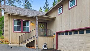 A two-story house with a front porch, a garage, and a staircase leading to the second floor. - Chalet di Montagna ~ Spacious house in the pines (Mi-Wuk Village)