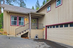 Ein zweistöckiges Haus mit Veranda, Garage und einer Treppe, die zum zweiten Stock führt.