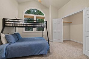 Un dormitorio con una cama litera, una ventana con persianas, un armario y una puerta.