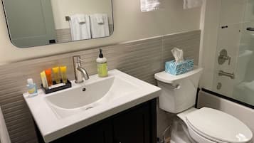 A bathroom with a white sink, a toilet, and a shower area.