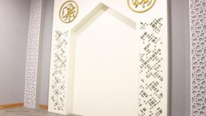 Een kamer met een witte scheidingswand voorzien van Arabische kalligrafie en geometrische patronen.