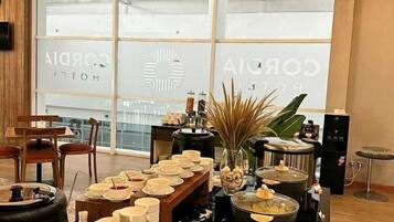 A hotel room with a large window, a dining table set with plates and glasses, and a kitchen area with pots and a stove.