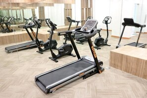 Ein Fitnessstudio mit verschiedenen Trainingsgeräten, darunter Laufbänder und Crosstrainer.
