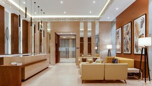 A hotel lobby with a reception desk, seating area, and artwork on the walls.