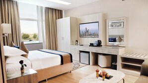 A hotel room with a bed, desk, and a small table with drinks. - Banan Hotel Suite (Tabuk)
