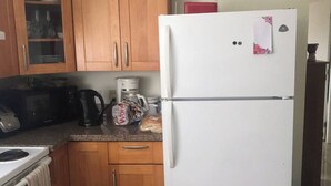 Una cocina con armarios de madera, un refrigerador blanco, una estufa y una cafetera.