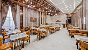 Un comedor amplio con varias mesas y sillas, un diseño moderno de techo y vistas al exterior a través de amplios ventanales.