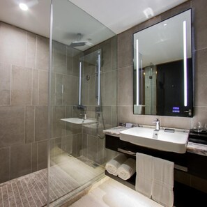 A modern bathroom with a glass-enclosed shower, a vanity with a sink, and a large mirror.
