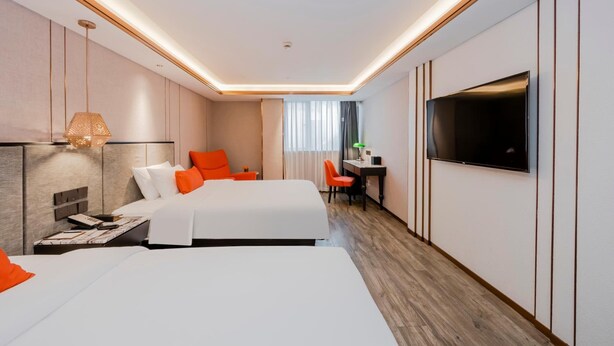 Habitación de hotel con dos camas, un escritorio, televisor y una ventana con cortinas.