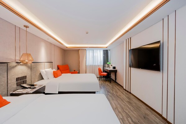 A hotel room with two beds, a desk, a television, and a window with curtains.