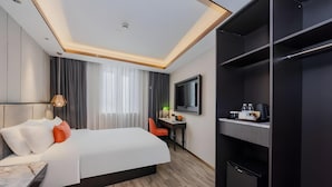 Una habitación de hotel con cama, escritorio, televisor y armario.