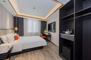 A hotel room with a bed, a desk, a TV, and a wardrobe.
