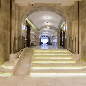 A grand staircase with illuminated steps leading to a high ceiling with chandeliers.