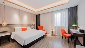 Una habitación de hotel con una cama grande, dos sillas, un escritorio y una mesita.