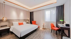 A hotel room with a large bed, two chairs, a desk, and a small table.