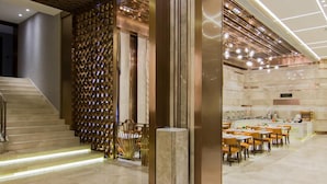 Un moderno vestíbulo de hotel con una escalera, una zona de estar y un comedor.