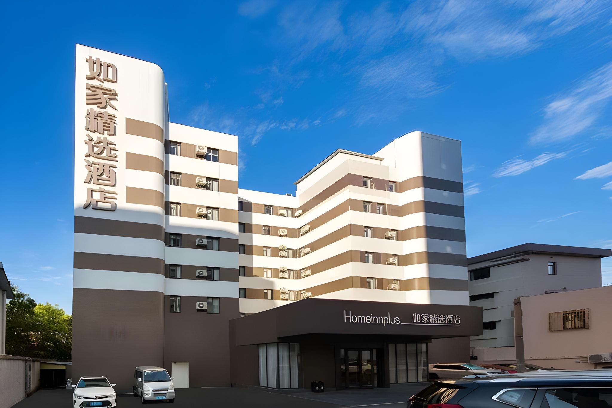 A multi-story hotel with a modern design, featuring a prominent signage for 'Homeinnplus' and a clear sky in the background.