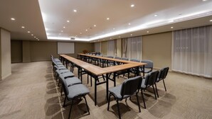 Une salle de conférence avec une longue table, des chaises, un écran de projection et un sol recouvert de moquette.
