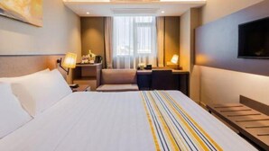 Une chambre d’hôtel avec un grand lit, des tables de chevet, un bureau et une télévision.