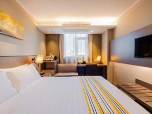 Habitació d'hotel amb un llit gran, taules de nit, escriptori i televisió.
