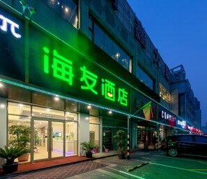 A hotel with a prominent green sign, large windows, and a paved entrance area. - Homeinn Plus (beijing Zhongguancun Wudaokou (Beijing)