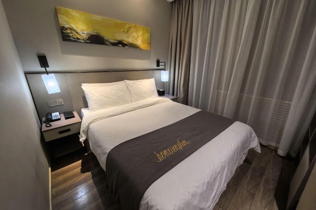 A hotel room with a bed, a nightstand, a telephone, and a painting on the wall.