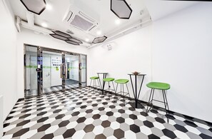 A modern interior with a checkered floor, glass doors, and green bar stools. - Homeinn Plus (beijing Zhongguancun Wudaokou (Beijing)