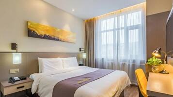 Habitación de hotel con una cama grande, mesitas de noche, un escritorio con silla, un cuadro en la pared y una ventana con cortinas.