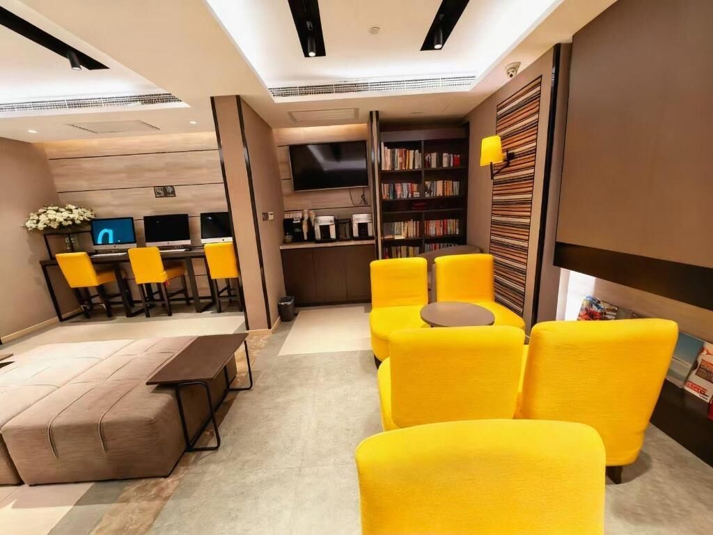 A modern living room with a sofa set, a coffee table, a flat-screen TV, and a bookshelf.