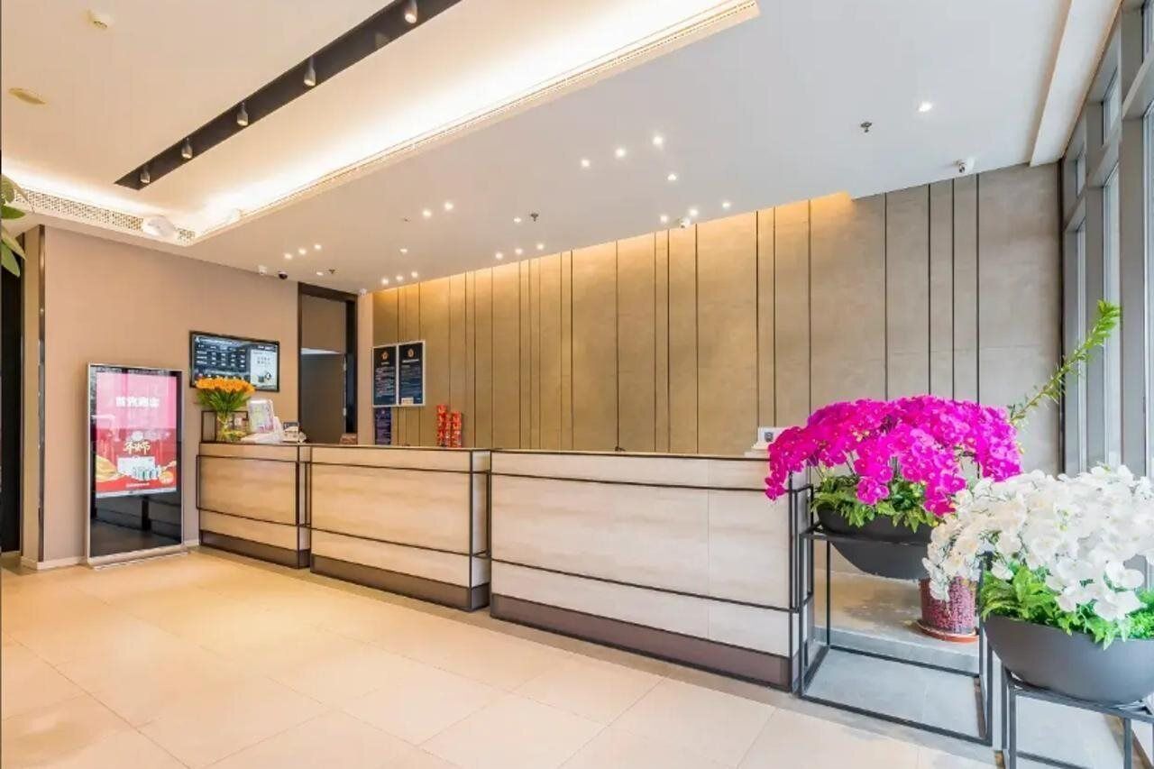 Ett välkomnande område med modern design, med en receptionsdisk, digital skärm och krukväxter.