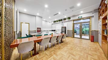 Un comedor moderno con una mesa de madera larga, varias sillas y una cocina al fondo.