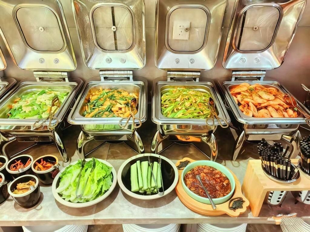 Un bufé con diversas opciones de comida, incluyendo verduras, mariscos y salsas.