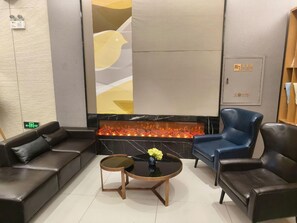 Un área de estar moderna con sofás de cuero, una mesa de centro redonda de madera y un jarrón decorativo.