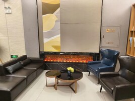 Un área de estar moderna con sofás de cuero, una mesa de centro redonda de madera y un jarrón decorativo.