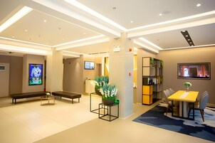 A modern hotel lobby with a reception desk, seating area, and a dining space.