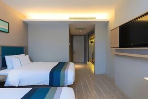 Una habitación de hotel con una cama, un televisor y una puerta que da a otra habitación.